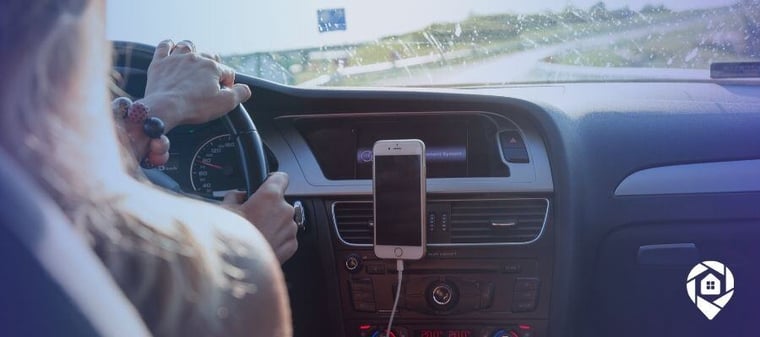 Person driving a car with a smartphone mounted on the dashboard.