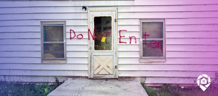 Condemned property with "Do Not Enter" spray painted on the vinyl siding.