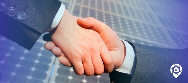 Solar professionals shaking hands over rooftop panels after closing more solar deals with debt consolidation.