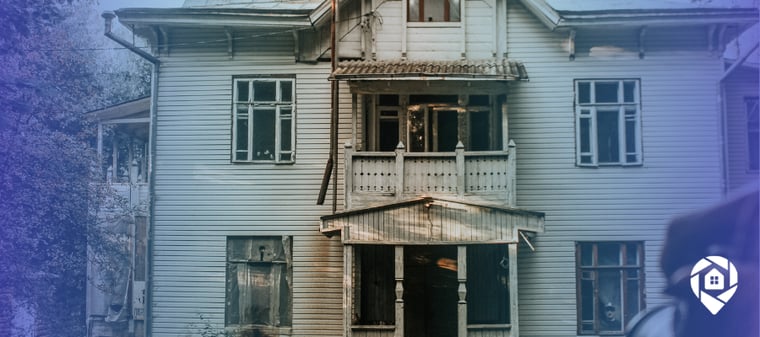 Weathered two-story house with boarded windows and a damaged porch, the kind of distressed property investors scout for deals.