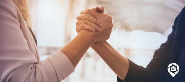 Two real estate professionals shaking hands on a win-win deal.