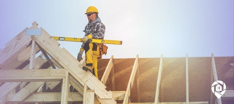 Construction worker using a level while building a wooden roof structure.
