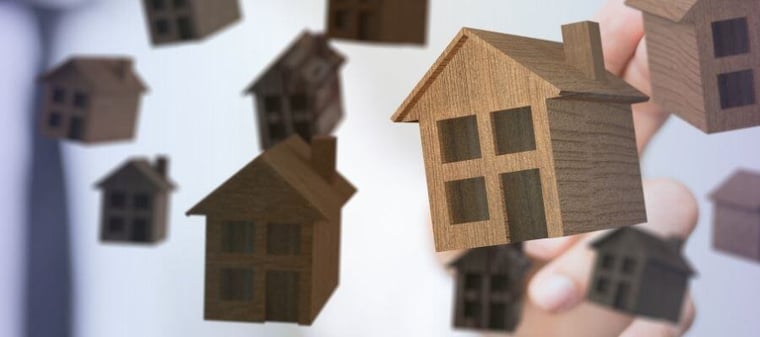 Floating wooden house models representing real estate investment opportunities.