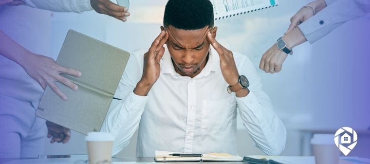 Overwhelmed man surrounded by tasks, holding his head in stress.