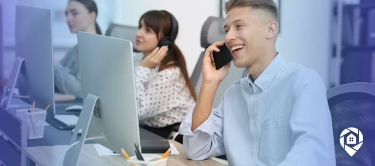 Real estate agent smiling while handling a seller call at the office.